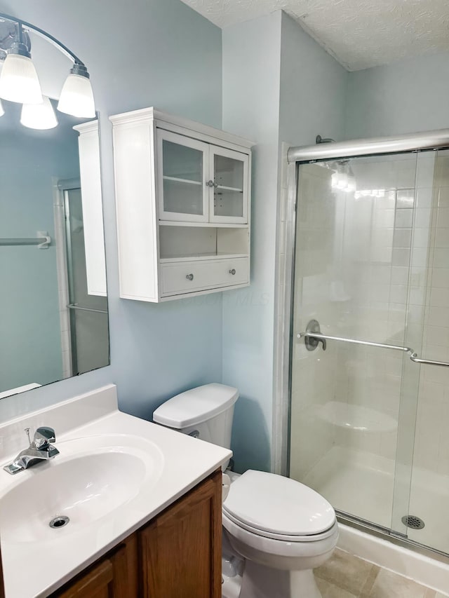 full bath with toilet, a stall shower, a textured ceiling, and vanity