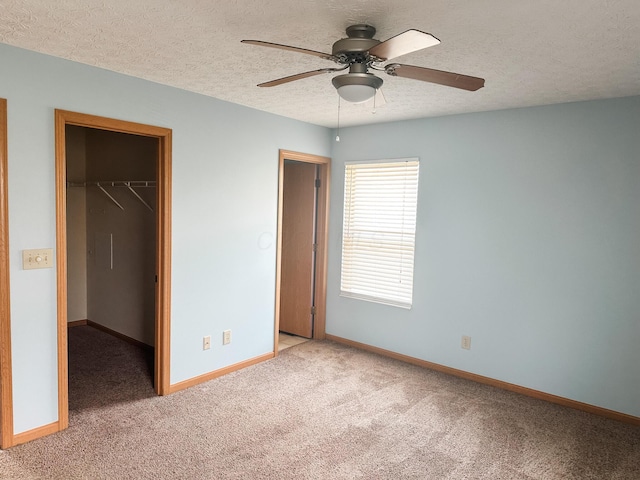unfurnished bedroom featuring a closet, baseboards, light carpet, and a spacious closet