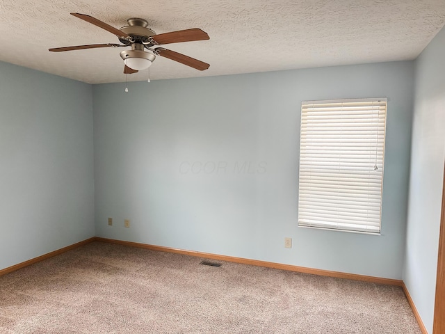 carpeted spare room with a ceiling fan, a healthy amount of sunlight, a textured ceiling, and baseboards