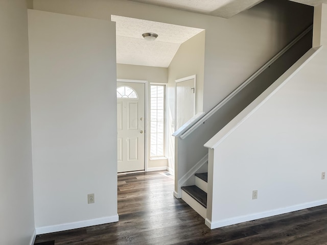 foyer featuring a textured ceiling, dark wood-style flooring, lofted ceiling, and baseboards