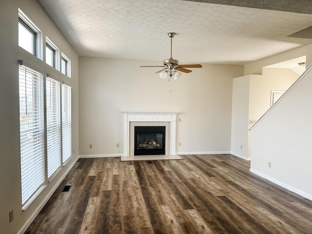 unfurnished living room featuring a tile fireplace, ceiling fan, visible vents, and dark wood-type flooring