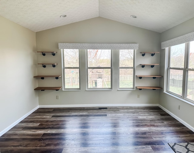 spare room with a textured ceiling, dark wood-style flooring, and vaulted ceiling