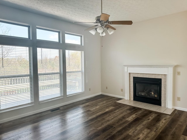 unfurnished living room with a fireplace, ceiling fan, visible vents, a textured ceiling, and wood finished floors