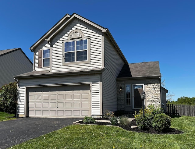 traditional-style home featuring fence, aphalt driveway, an attached garage, and stone siding