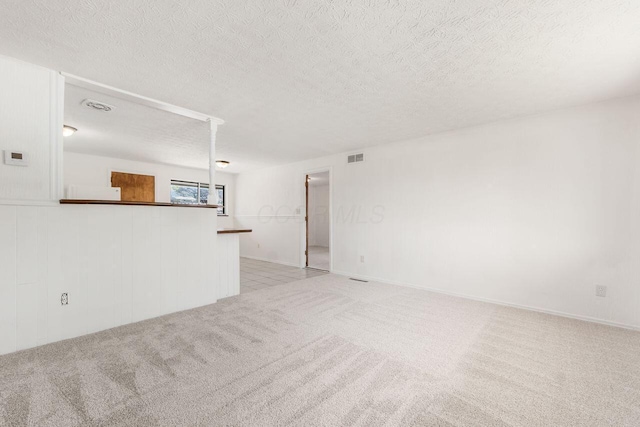 6350 Roselawn Ave, Reynoldsburg, OH 43068 - unfurnished living room featuring light colored carpet, a textured ceiling, and visible vents