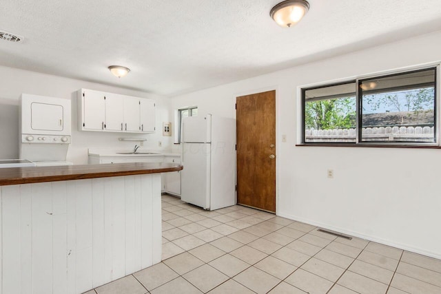 6350 Roselawn Ave, Reynoldsburg, OH 43068 - kitchen with stacked washer / drying machine, freestanding refrigerator, a sink, and visible vents