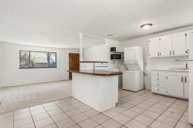 6350 Roselawn Ave, Reynoldsburg, OH 43068 - kitchen with open floor plan, white cabinetry, light colored carpet, stacked washing maching and dryer, and light tile patterned floors