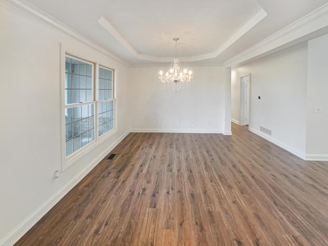 unfurnished dining area featuring an inviting chandelier, a raised ceiling, wood finished floors, visible vents, and baseboards