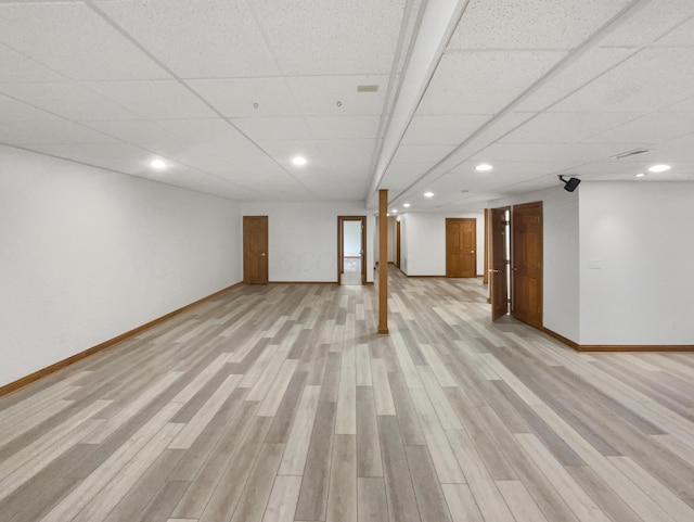 finished basement featuring light wood finished floors, baseboards, recessed lighting, and a drop ceiling