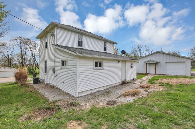 back of house featuring an outdoor structure, a detached garage, and central air condition unit