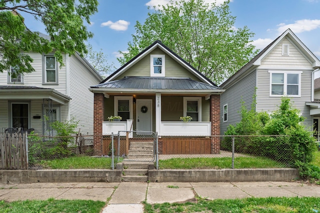 238 E Barthman Ave, Columbus, OH 43207 - view of front of property with a porch, a fenced front yard, brick siding, and metal roof