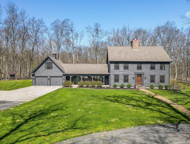 view of front of property featuring a garage, a chimney, a front yard, and concrete driveway
