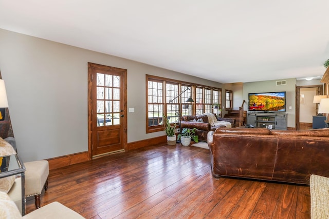 living area with baseboards, visible vents, and hardwood / wood-style flooring