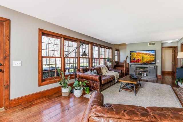 living room featuring hardwood / wood-style floors, visible vents, and baseboards