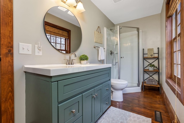 full bathroom with toilet, visible vents, wood finished floors, a shower stall, and vanity
