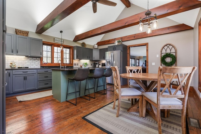 dining space with dark wood finished floors, ceiling fan, vaulted ceiling with beams, and visible vents