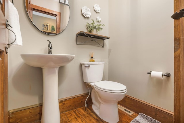 bathroom featuring toilet, wood finished floors, and baseboards