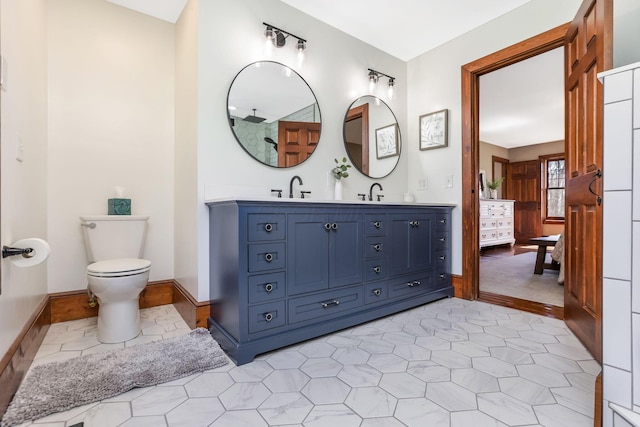 bathroom featuring baseboards, a sink, double vanity, and toilet