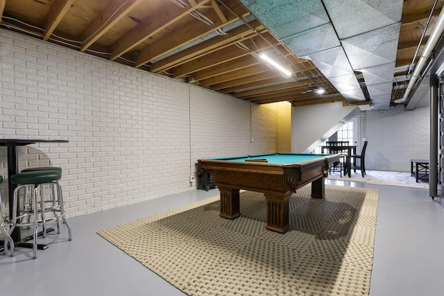 playroom featuring brick wall, concrete flooring, and pool table
