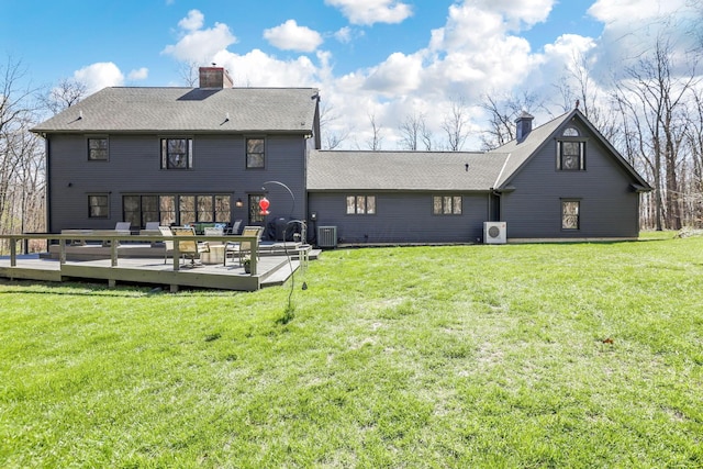 back of house with a chimney, a deck, and a lawn