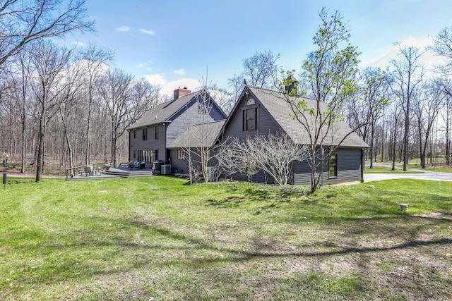 view of home's exterior with a lawn and a shingled roof