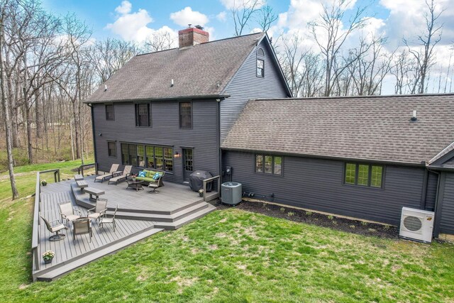 back of house with roof with shingles, a chimney, a wooden deck, an outdoor hangout area, and a yard