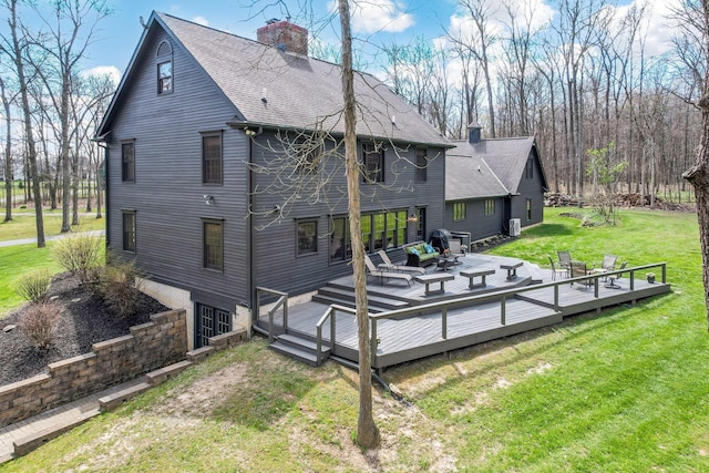 back of property featuring a lawn, a shingled roof, a chimney, and a deck