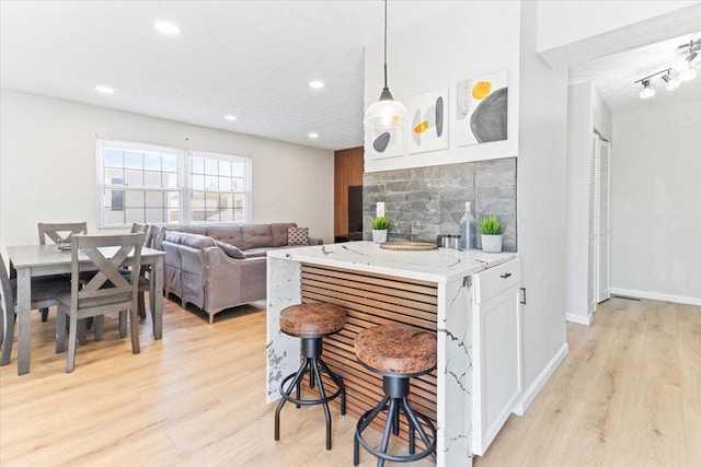 kitchen featuring recessed lighting, a kitchen bar, and light wood-style floors