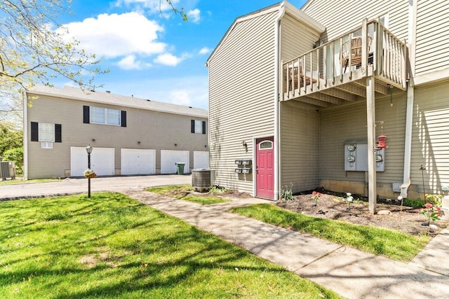 rear view of property featuring a lawn, central AC, and a balcony