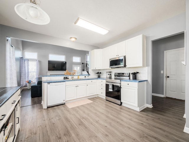 kitchen featuring a sink, appliances with stainless steel finishes, white cabinetry, and a healthy amount of sunlight