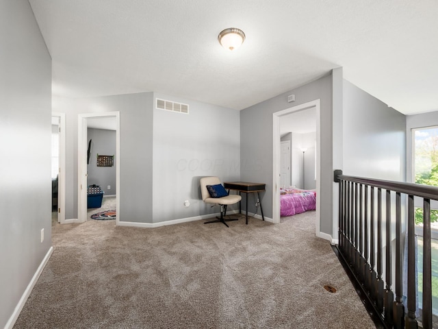 hallway with baseboards, carpet, and visible vents