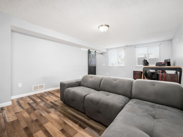 living area with baseboards, visible vents, a barn door, and wood finished floors