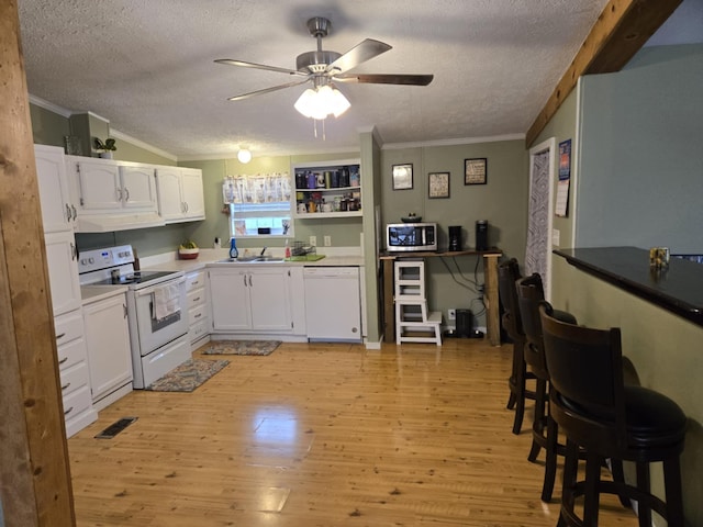 9330 Pidcock Rd, Zanesville, OH 43701 - kitchen featuring white appliances, crown molding, under cabinet range hood, a textured ceiling, and light wood finished floors