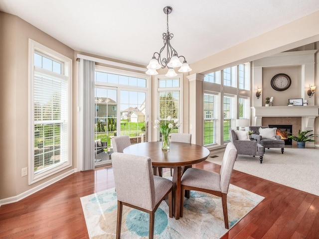 7766 Dickens Ct, Delaware, OH 43015 - dining area with dark wood-type flooring, a wealth of natural light, a lit fireplace, and a notable chandelier