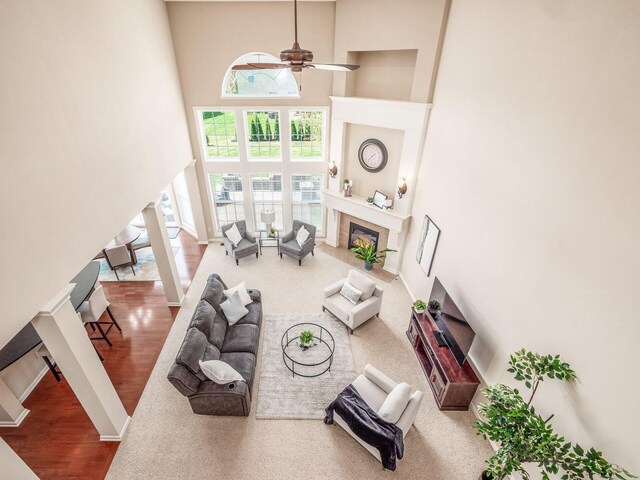 7766 Dickens Ct, Delaware, OH 43015 - living room featuring wood finished floors, a ceiling fan, a towering ceiling, and a fireplace