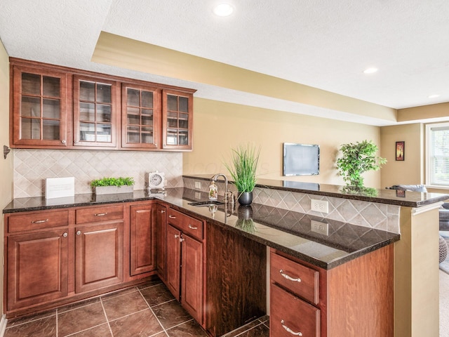 7766 Dickens Ct, Delaware, OH 43015 - kitchen with a peninsula, a sink, backsplash, and glass insert cabinets