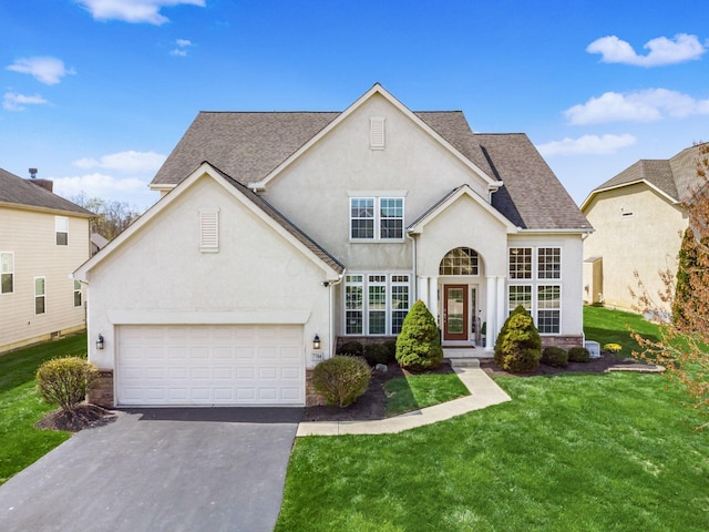 7766 Dickens Ct, Delaware, OH 43015 - view of front of house featuring a front lawn, aphalt driveway, roof with shingles, and stucco siding