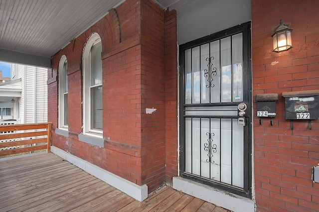entrance to property with covered porch and brick siding
