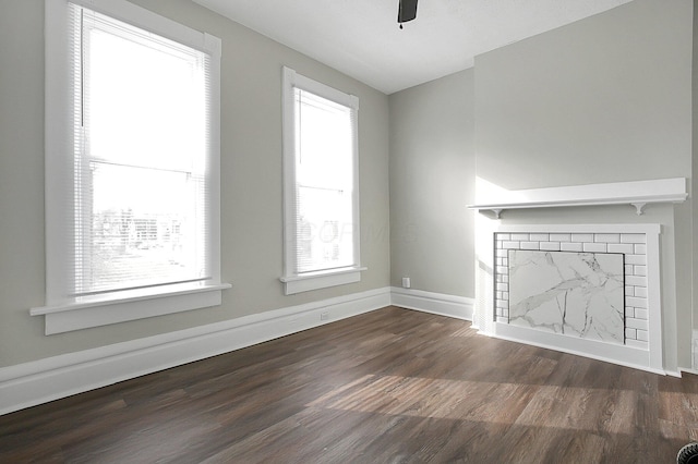 unfurnished living room featuring baseboards, a ceiling fan, wood finished floors, and a fireplace