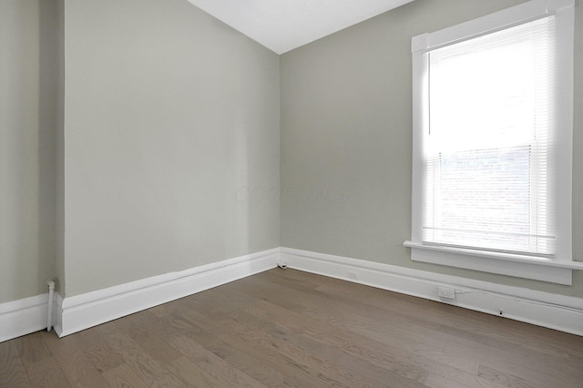 empty room featuring vaulted ceiling, baseboards, and dark wood-type flooring
