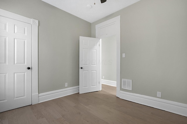 unfurnished bedroom featuring ceiling fan, baseboards, wood finished floors, and visible vents