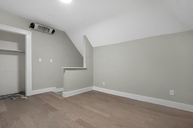 bonus room featuring visible vents, baseboards, vaulted ceiling, and wood finished floors