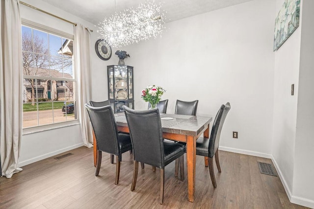 dining area featuring wood finished floors, visible vents, and baseboards