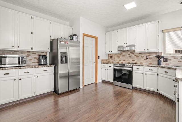 kitchen with white cabinets, dark wood-style flooring, appliances with stainless steel finishes, and under cabinet range hood