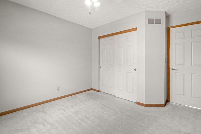 unfurnished bedroom featuring carpet, visible vents, a closet, baseboards, and a textured ceiling
