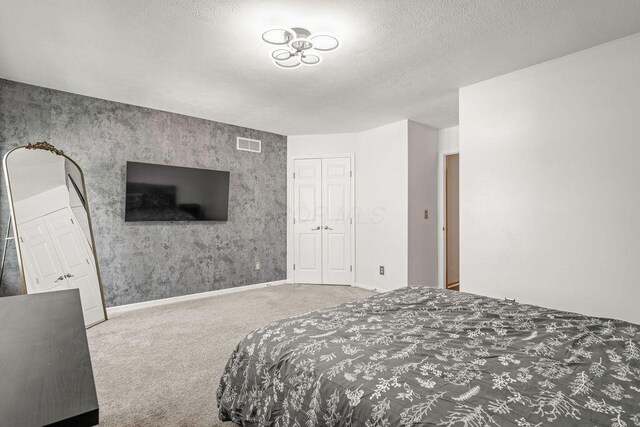 bedroom with baseboards, visible vents, carpet floors, and a textured ceiling
