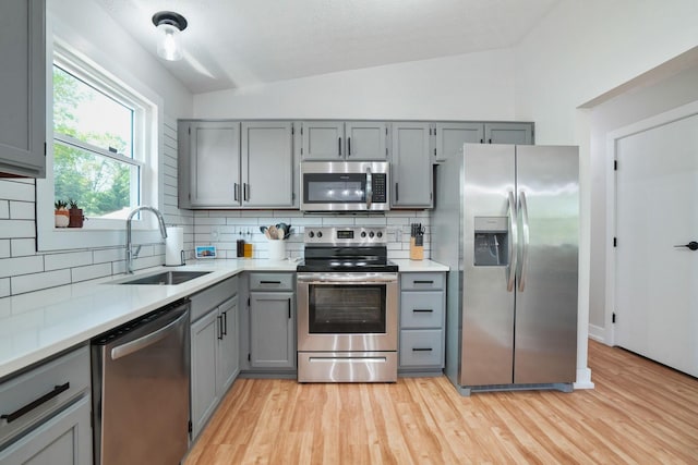 5133 Hidden View Dr, Hilliard, OH 43026 - kitchen featuring appliances with stainless steel finishes, gray cabinets, a sink, decorative backsplash, and light wood-type flooring