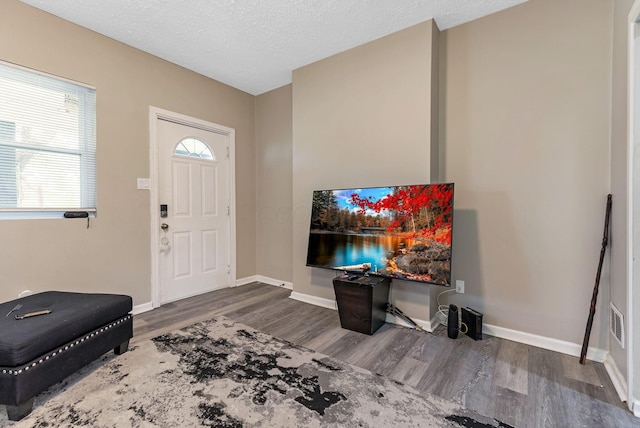 foyer entrance with baseboards, wood finished floors, and a textured ceiling