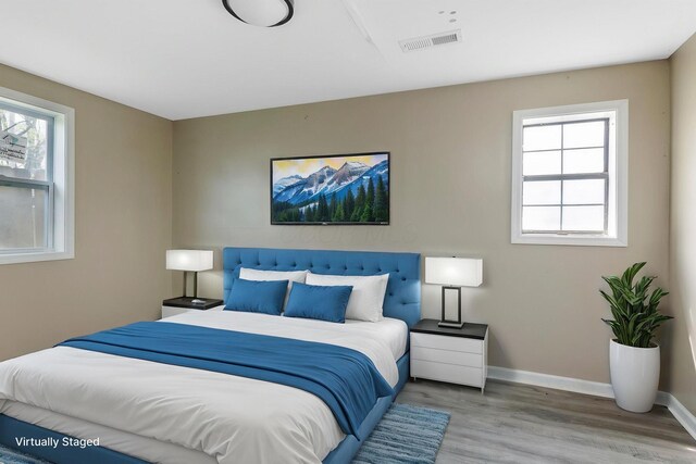 bedroom with baseboards, visible vents, and wood finished floors