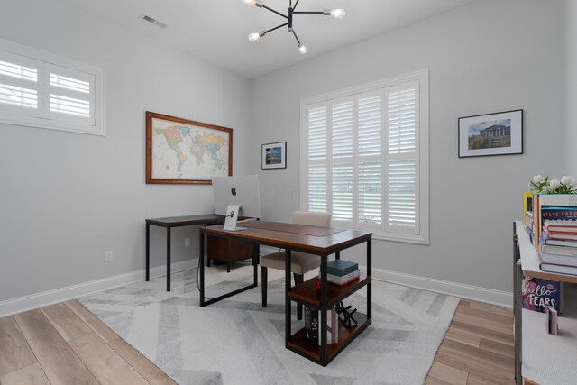 home office with baseboards, visible vents, light wood finished floors, and a notable chandelier